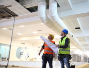 Construction workers looking at blueprints inside construction site.