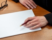 female-left-hand-with-pen-blank-paper-close-up-wooden-office-table-write-sign-concept_771335-1536