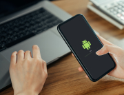 Woman hand holding smartphone with blank copy space screen for your advertisement. laptop on the table.